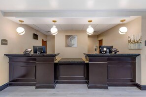 En receptionsdisk med en platt-TV, en kassa och en betalterminal. Ovanför disken hänger två hänglampor, och på väggen finns en stor, abstrakt målning.