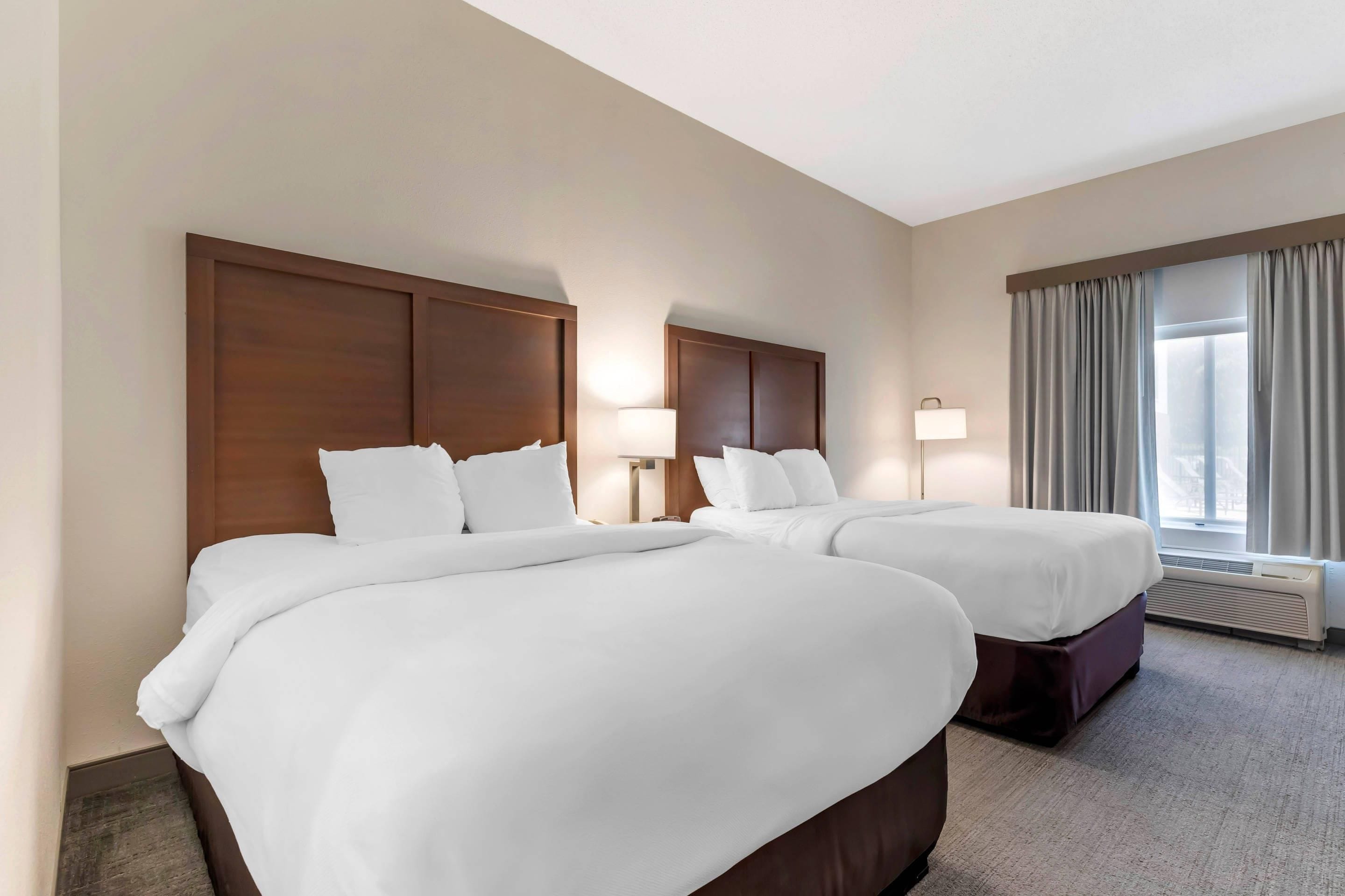 Une chambre d’hôtel avec deux lits, une grande fenêtre avec des rideaux et un radiateur fixé au mur.