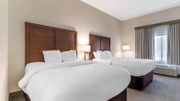 Une chambre d’hôtel avec deux lits, une grande fenêtre avec des rideaux et un radiateur fixé au mur.