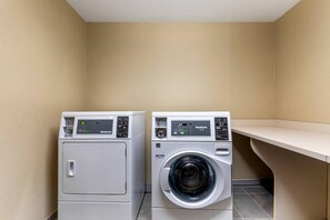 Two front-loading washing machines in a laundry room with a beige wall and a white ceiling.