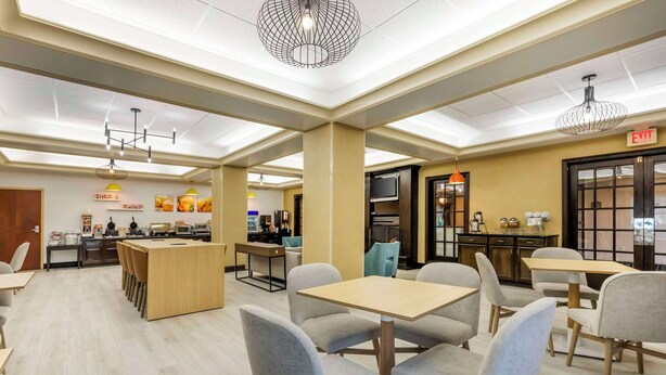 A modern dining area with a central island, multiple tables, and chairs. There are signs for 'RISP' and 'SILVER' on the wall, and an 'EXIT' sign above a door. - Comfort Inn & Suites Chestertown (Chestertown)