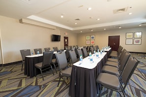 A conference room with a long table, chairs, water bottles, and framed pictures on the wall.