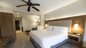 A hotel room with a large bed, a desk, a chair, a ceiling fan, and a nightstand with a phone. - Holiday Inn Express Clinton by IHG (Clinton)