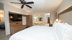 A hotel room with a large bed, a TV, a ceiling fan, a bathroom with a mirror, and a desk with a lamp. - Holiday Inn Express Clinton by IHG (Clinton)