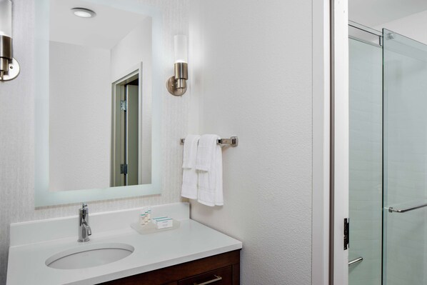 A modern bathroom with a white sink, a large mirror, and a glass shower enclosure.