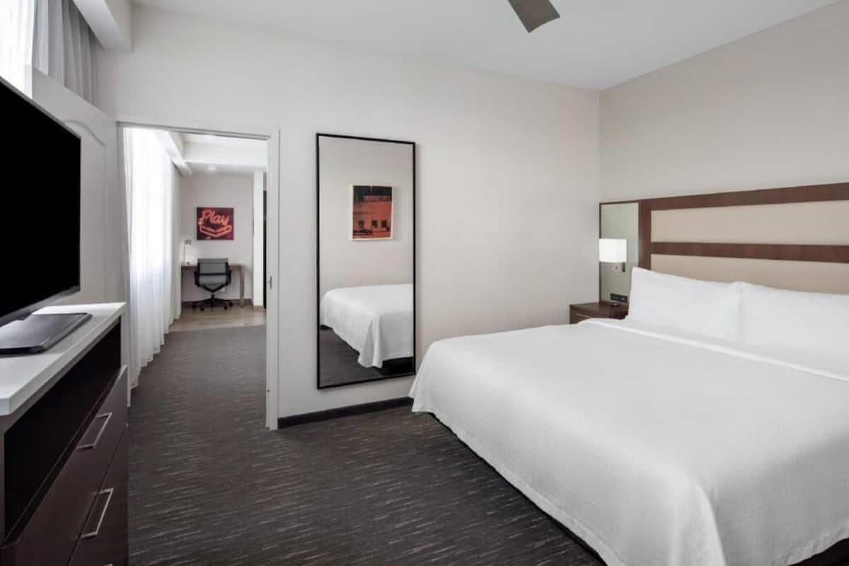 Une chambre d’hôtel avec un grand lit, une télévision, un bureau et un miroir.