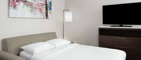 Habitación de hotel con cama, televisor de pantalla plana, cómoda y un cuadro abstracto moderno en la pared.