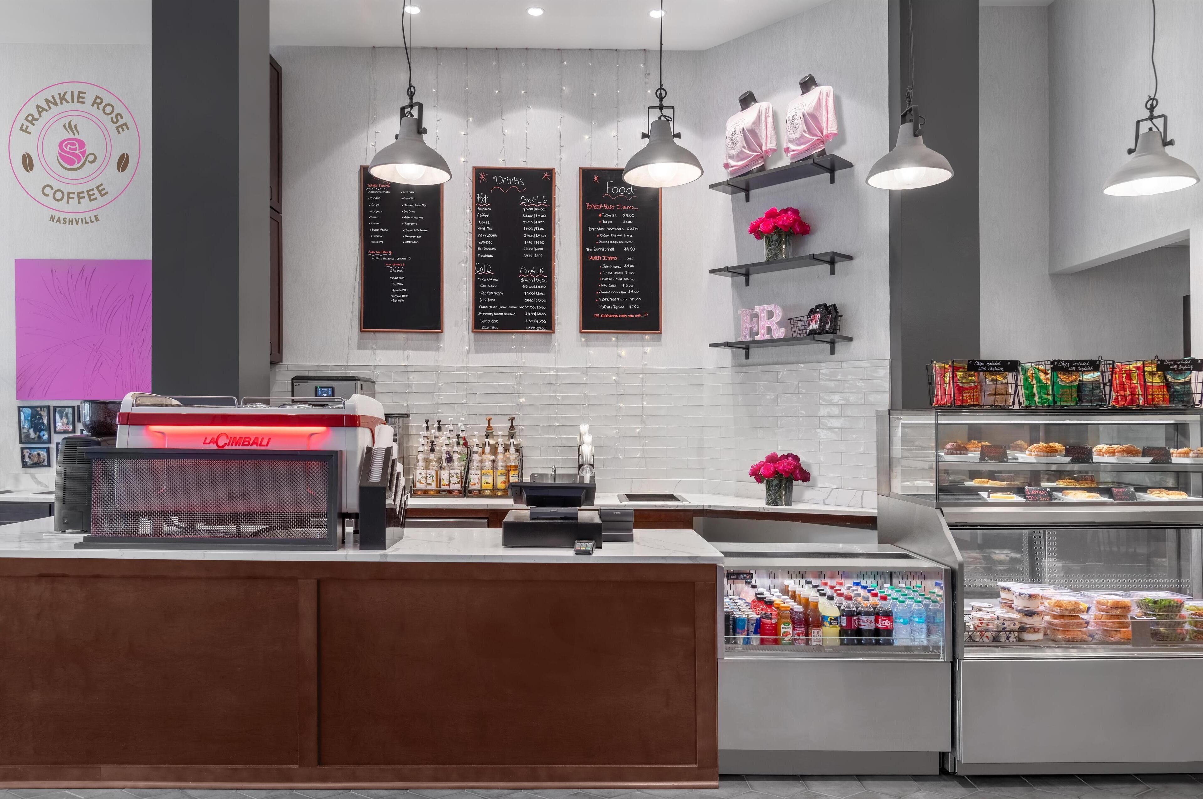 Interieur van een koffiebar met een balie, menukaarten en een vitrine met snacks.