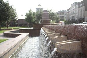 Un élément décoratif aquatique composé de plusieurs niveaux d’eau en cascade, entouré d’un mur de pierre et de verdure.