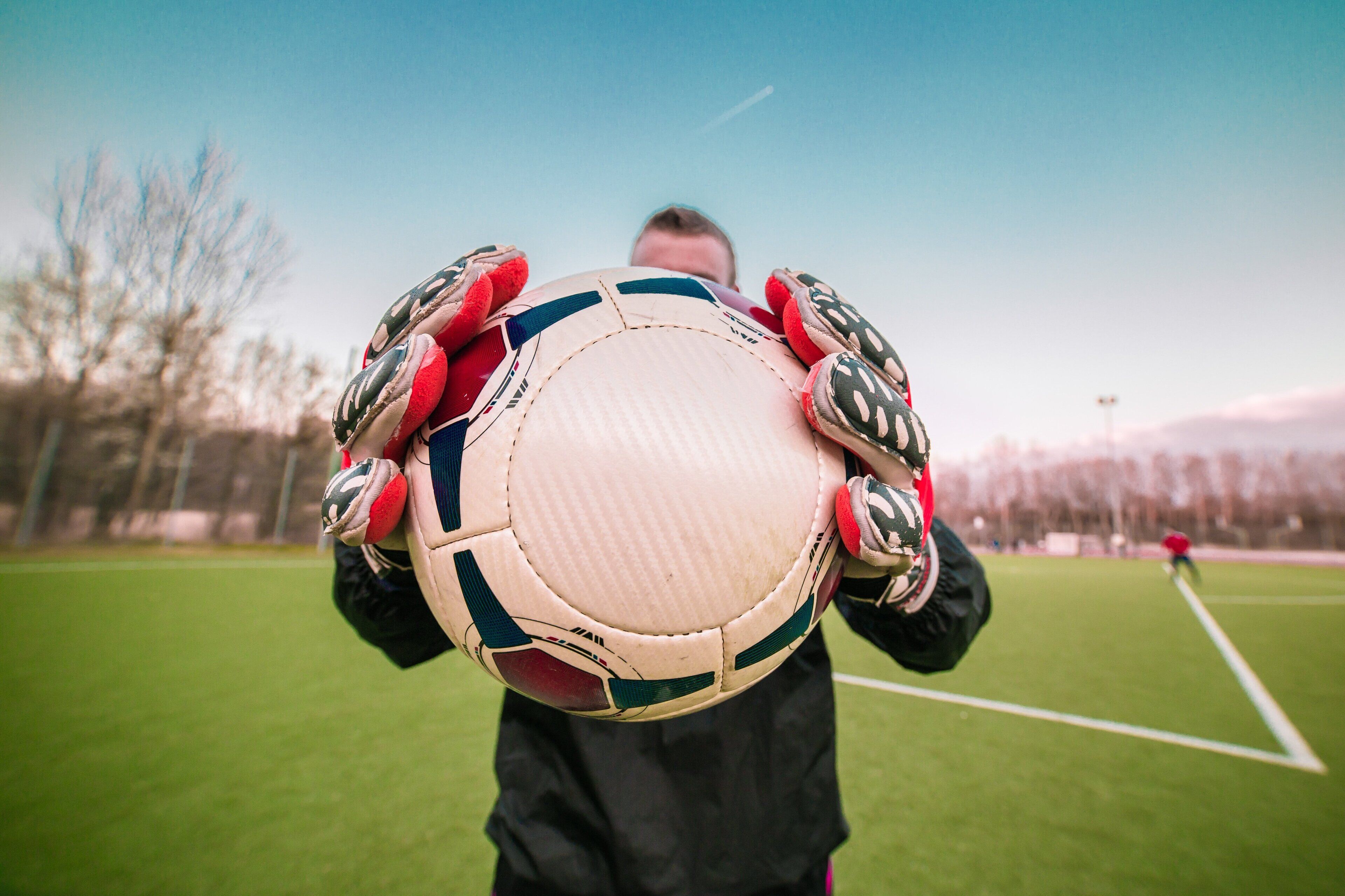 A person holding a soccer ball on a grassy field.