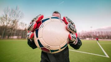 A person holding a soccer ball on a grassy field.