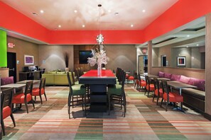 Un'area pranzo moderna con un tavolo centrale, diverse disposizioni di posti a sedere e un elemento decorativo.