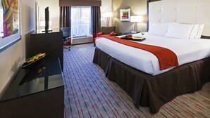 Una habitación de hotel con una cama grande, un escritorio con ordenador, una silla y un televisor.
