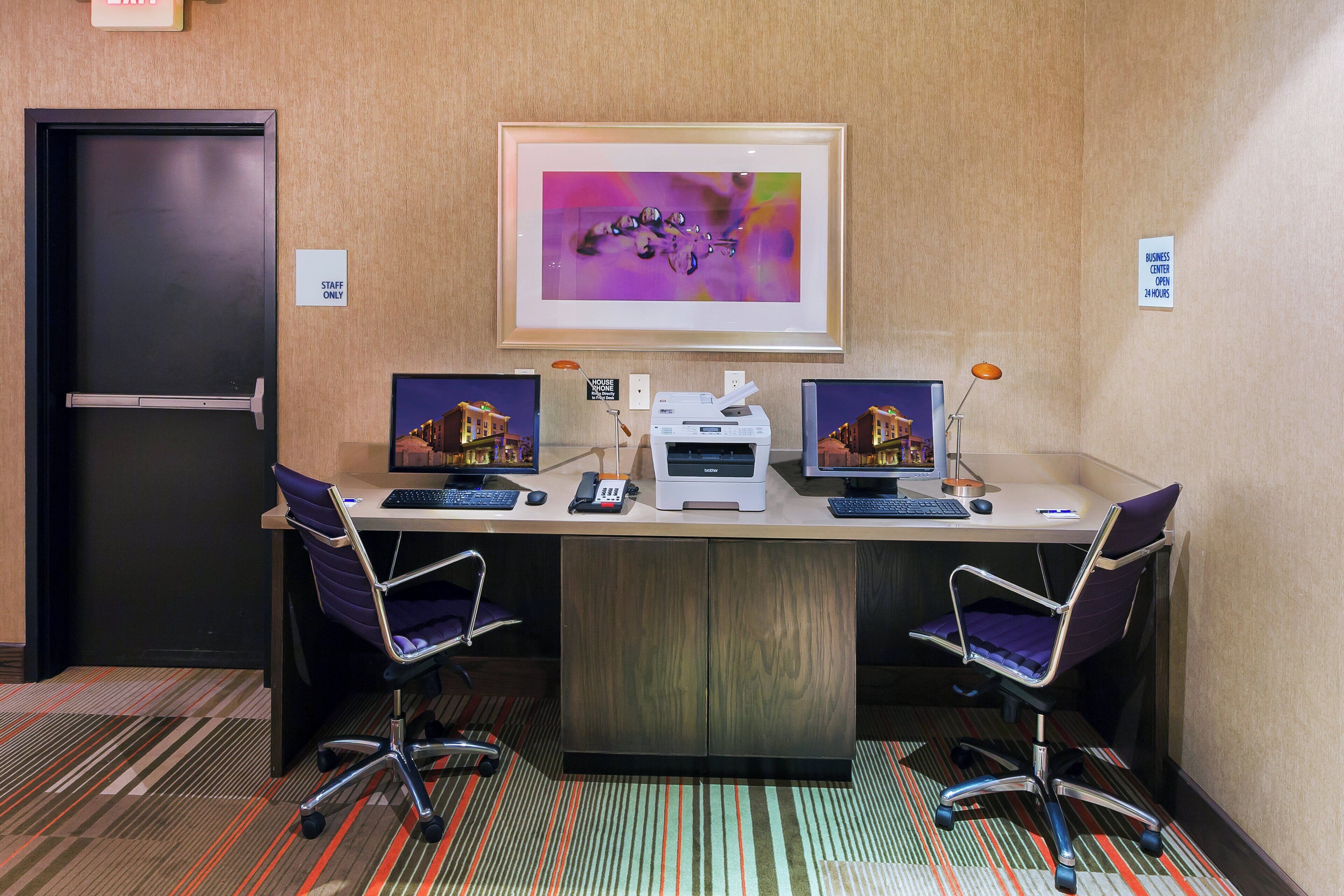 A conference room with a long table, two chairs, a printer, and a framed abstract artwork on the wall.