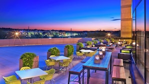 A rooftop terrace with outdoor seating, a view of the city skyline, and a modern building facade. - Le Meridien Arlington (Arlington)