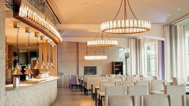 A modern hotel lobby with a curved reception desk, multiple pendant lights, and a fireplace. - Le Meridien Arlington (Arlington)