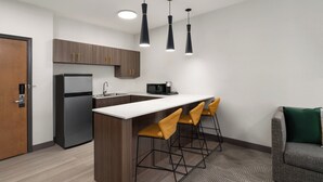 A modern kitchen with a refrigerator, microwave, and bar stools. - Holiday Inn Laramie by IHG (Laramie)