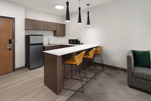 Cocina moderna con refrigerador, microondas y taburetes de bar.