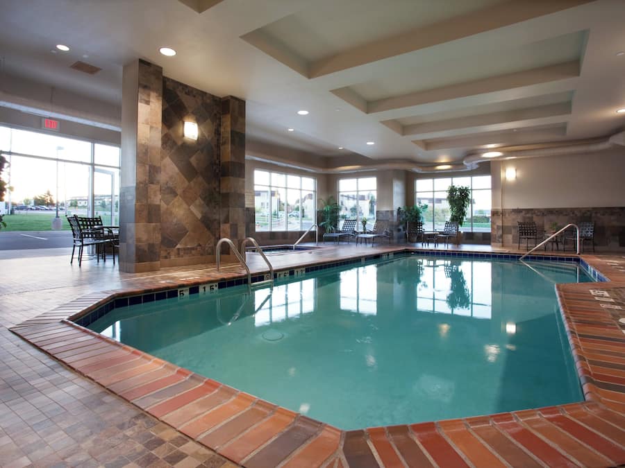 A large indoor swimming pool with clear water, surrounded by tiled walls and a brick floor.