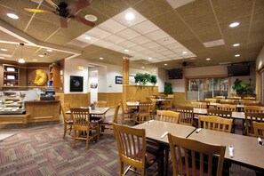 A restaurant with wooden tables and chairs, a counter with food display, and ceiling fans. - Holiday Inn Laramie by IHG (Laramie)