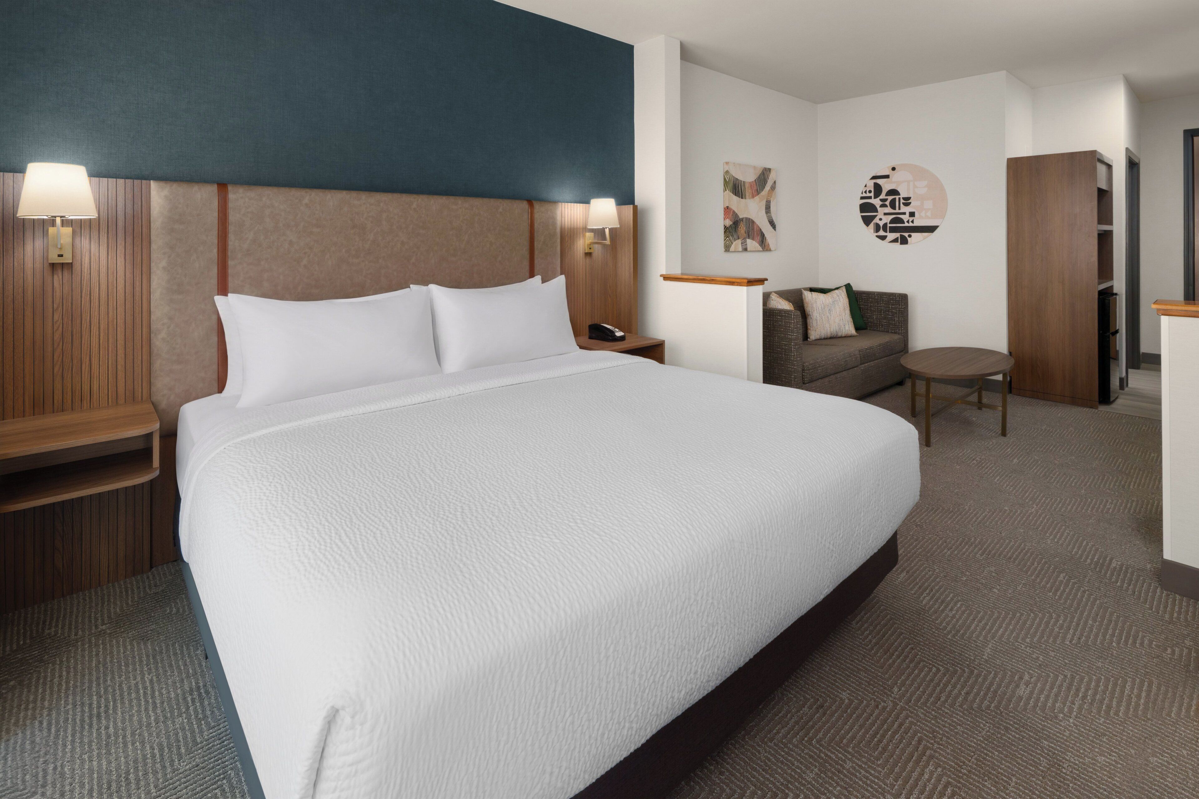 Ein Hotelzimmer mit einem großen Bett, einer Couch, einem kleinen Tisch und einem Schrank.