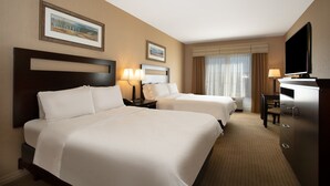 A hotel room with two beds, a TV, a desk, and a window with curtains. - Holiday Inn Laramie by IHG (Laramie)