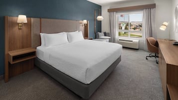 A hotel room with a large bed, bedside tables, a desk, and a window with a view.