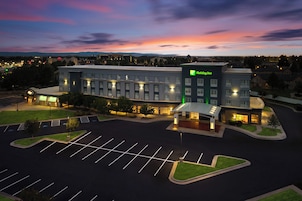 Un hotel Holiday Inn con un estacionamiento y un atardecer de fondo.