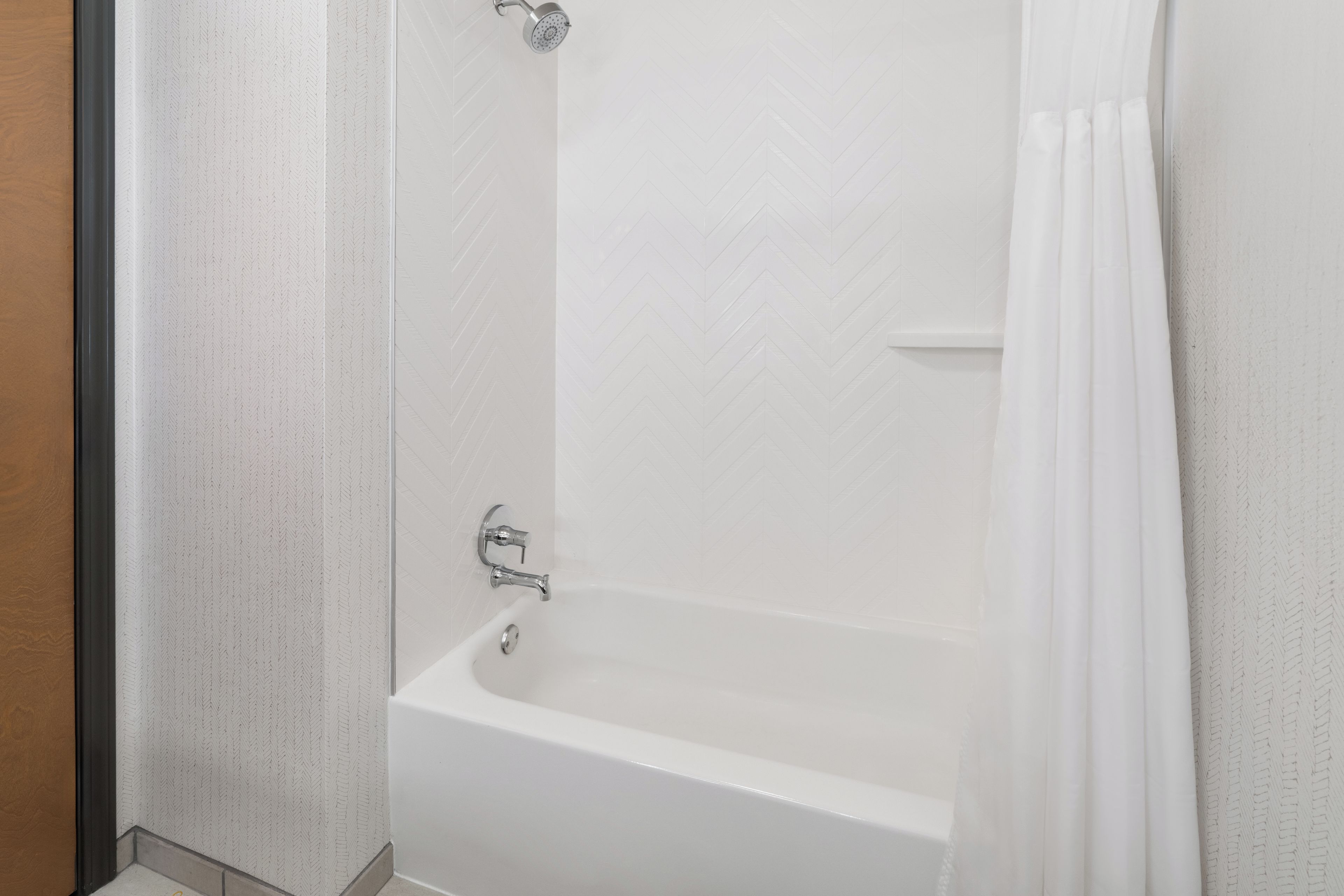 Eine weiße Badewanne mit Duschkopf und Vorhang.