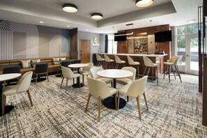 A modern bar area with seating, a bar counter, and a television screen. - Holiday Inn Laramie by IHG (Laramie)