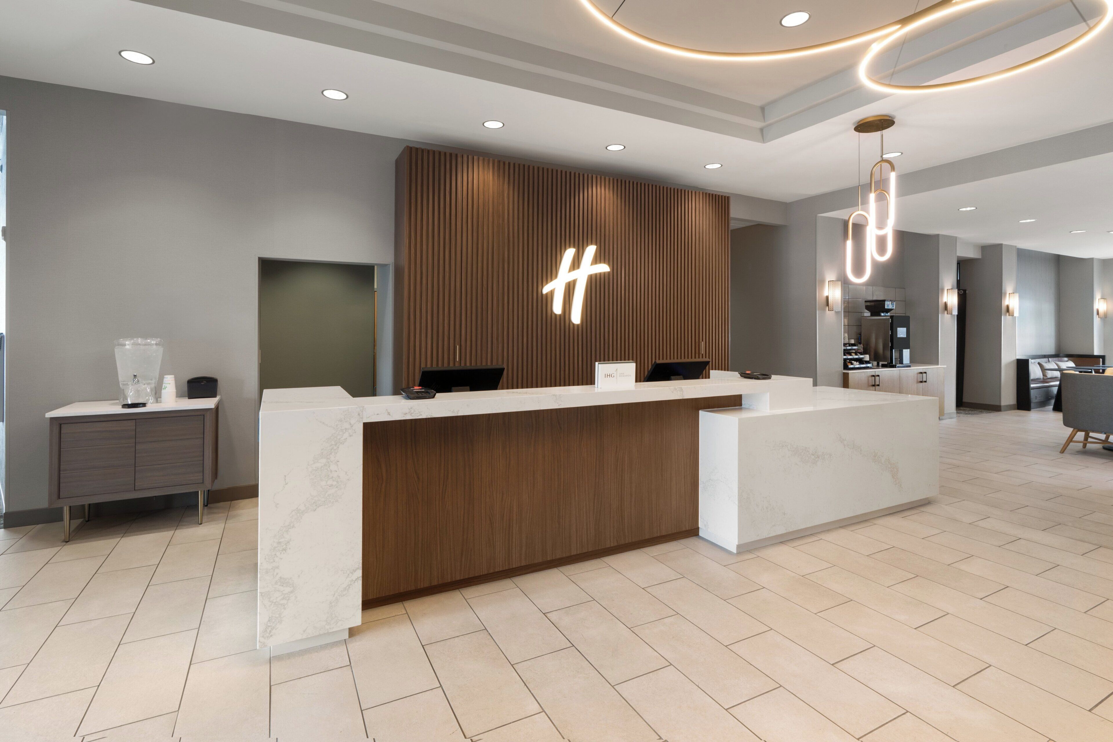Un mostrador de recepción moderno con detalles de madera, un llamativo logotipo 'H' y un diseño limpio y minimalista.