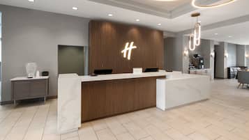 Un mostrador de recepción moderno con detalles de madera, un llamativo logotipo 'H' y un diseño limpio y minimalista.