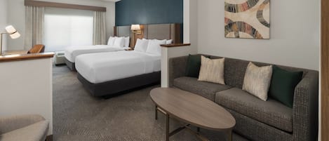 Una habitación de hotel con una cama, un sofá, una mesita y un escritorio con una lámpara.