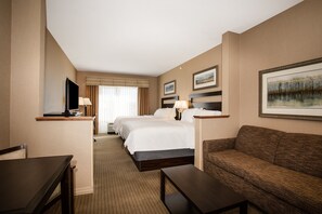 A hotel room with two beds, a sofa, a TV, and a desk.