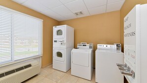 A laundry room with stacked washers and dryers, a vented heater, and a window with blinds. - Holiday Inn Laramie by IHG (Laramie)