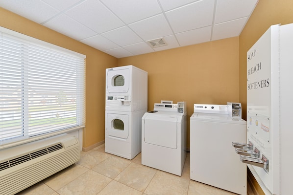 A laundry room with stacked washers and dryers, a vented heater, and a window with blinds. - Holiday Inn Laramie by IHG (Laramie)
