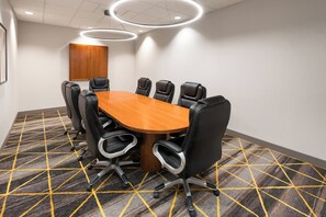 A conference room with a wooden table, black chairs, and a patterned carpet. - Holiday Inn Laramie by IHG (Laramie)