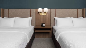Quarto de hotel com duas camas, uma mesa de cabeceira com abajur e um telefone.