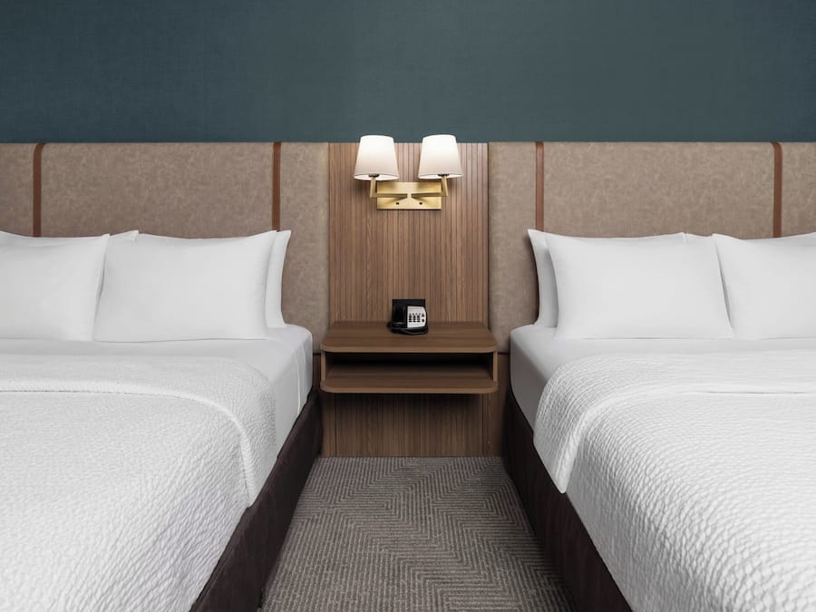 Ein Hotelzimmer mit zwei Betten, einem Nachttisch mit Lampe und einem Telefon.