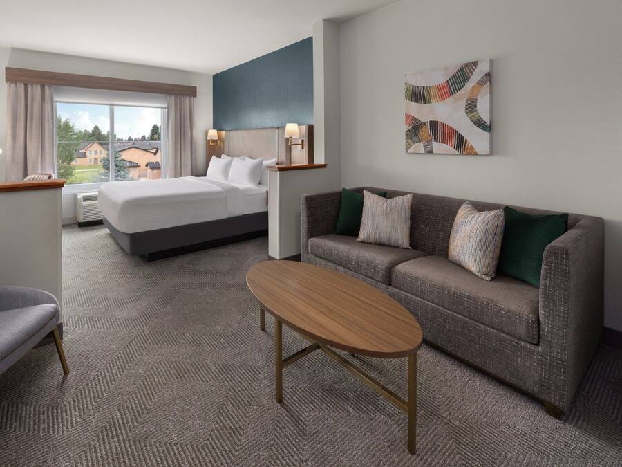 Ett hotellrum med en säng, en soffa, ett soffbord och en tavla på väggen.