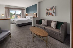 A hotel room with a bed, a sofa, a coffee table, and a painting on the wall. - Holiday Inn Laramie by IHG (Laramie)