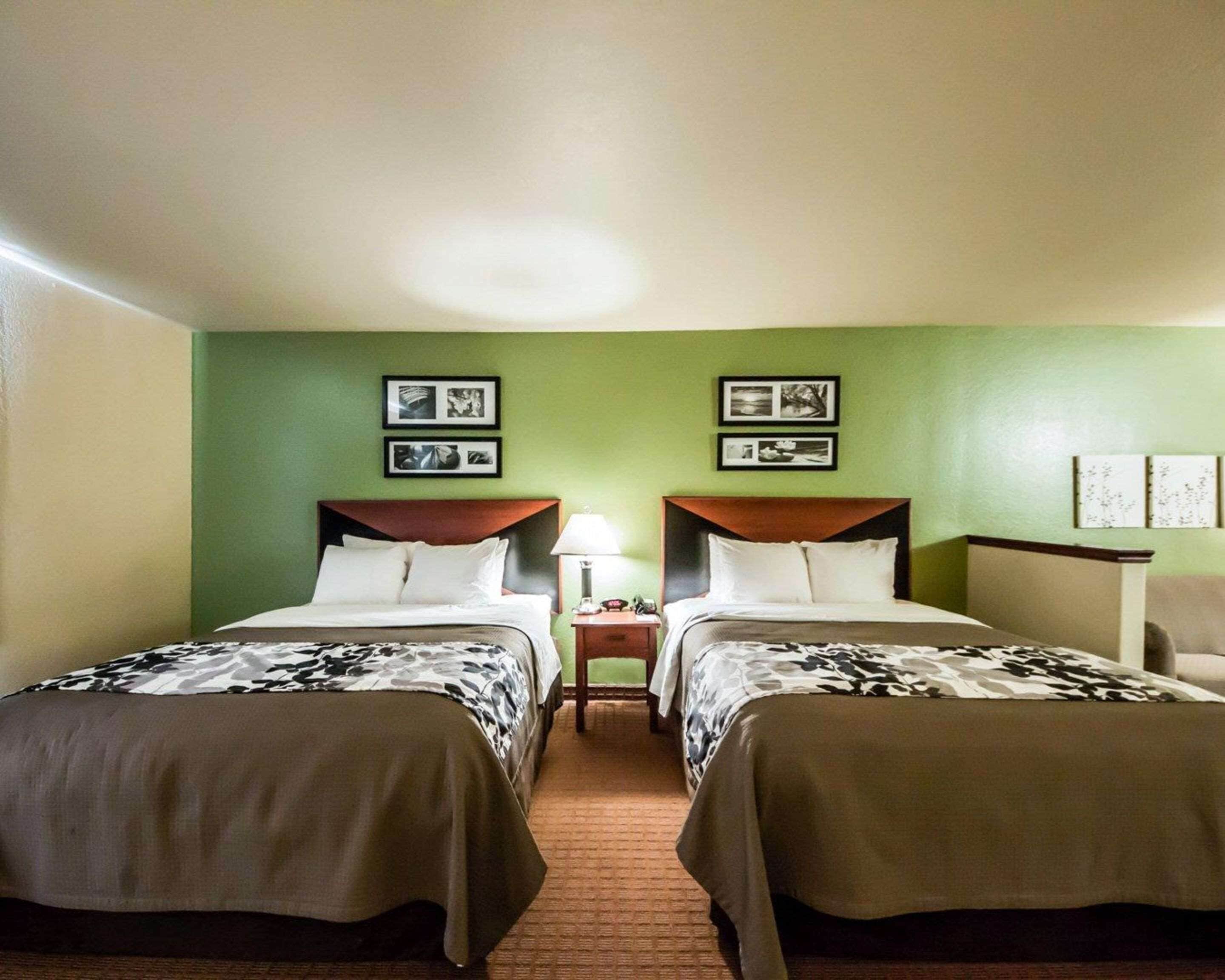 A hotel room with two beds, green walls, and framed pictures on the wall.