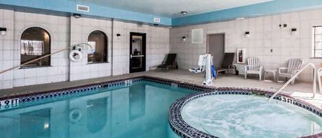 Una piscina interior con hidromasaje, paredes con azulejos y sillones de descanso.