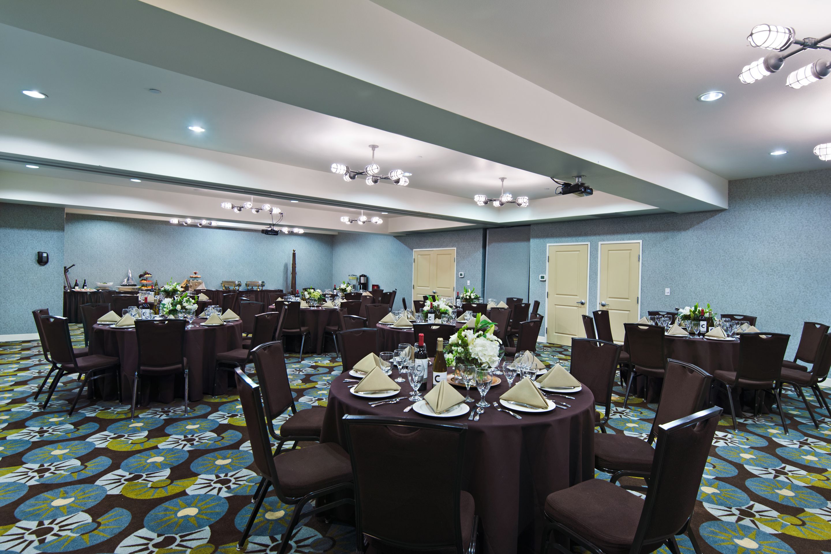 A conference room with multiple round tables, each set with chairs, plates, and cutlery.