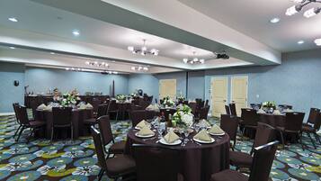 A conference room with multiple round tables, each set with chairs, plates, and cutlery.