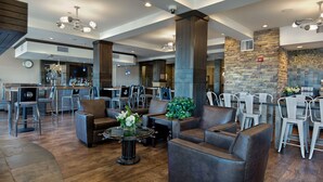Un'ampia hall con divani in pelle, angolo bar e parete decorata in pietra.