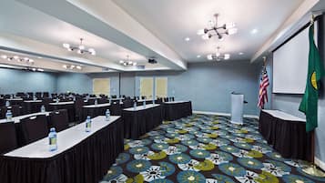 Une salle de conférence avec de longues tables, des chaises et un tapis à motifs.