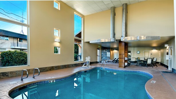 An indoor swimming pool with clear water, a lifeguard chair, and a sunroof. - Oxford Suites Silverdale (Silverdale)