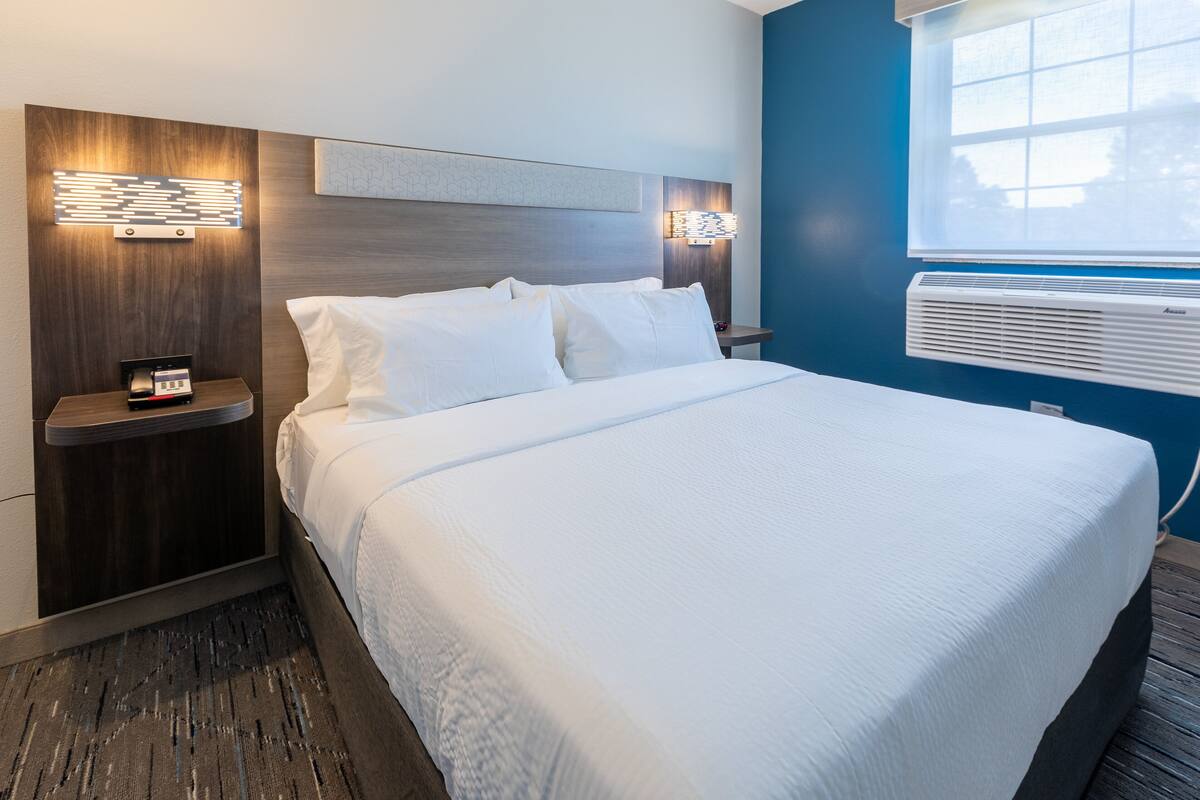 A neatly made bed with white linens, a wooden headboard, and two bedside tables with lamps.