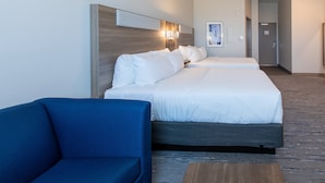 A hotel room with two beds, a blue sofa, and a wooden coffee table. - Holiday Inn Express & Suites Englewood Denver South by IHG (Englewood)